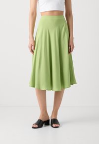 Lysegrønn, luftig midiskjørt laget av myk chiffon med en jevn tekstur og elastisk liv. Kombinert med svarte hælede sandaler.