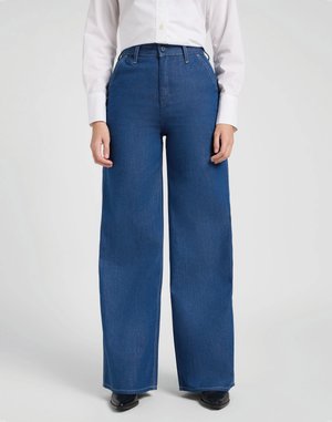 Celana denim biru model lebar dengan pinggang tinggi, dilengkapi dengan loop sabuk dan penutup kancing, dipadukan dengan kemeja putih lengan panjang.