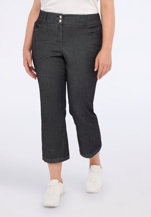 Donkergrijze cropped broeken met een gladde textuur, voorzien van twee decoratieve knopen bij de taille en zakken aan de voorkant. Gecombineerd met witte sneakers.