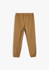 Pantalons en mélange de coton marron avec une taille élastique et des poignets froncés aux chevilles, présentant une texture lisse et un design simple.