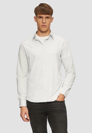 Witte overhemd met dunne blauwe strepen, lange mouwen, knoopmanchetten en een gebogen zoom. Gecombineerd met donkere jeans voor contrast.