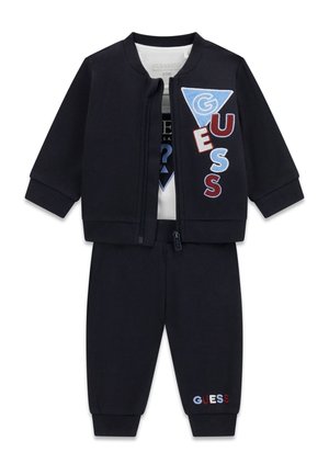 Czarny, trzyczęściowy strój dla malucha z kurtką na zamek, białą koszulą i spodniami z wielokolorowymi naszywkami z logo "GUESS".