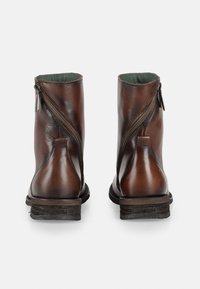 Bruine leren enkelboots met een zijrits, textuurfinish, subtiele glans en groene binnenvoering; lage gestapelde hak.