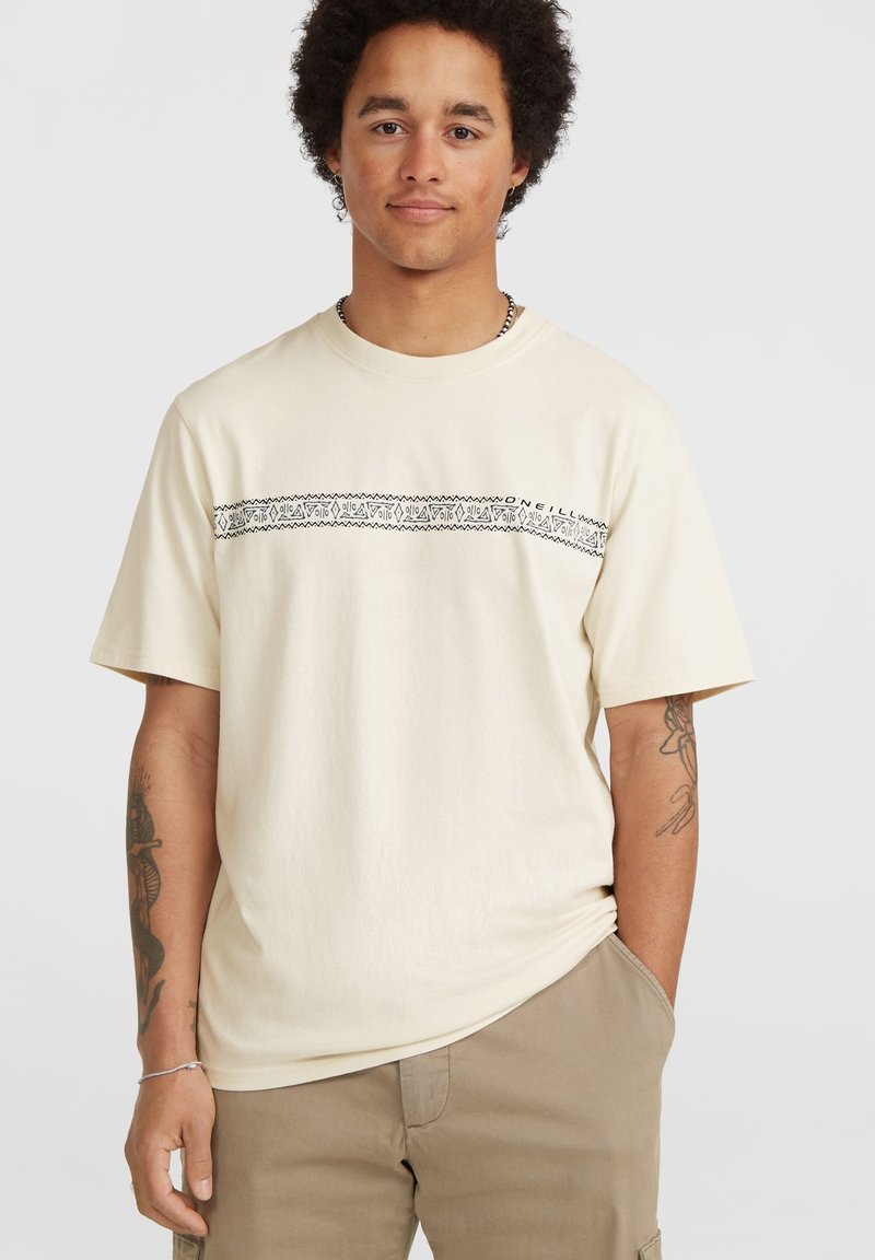 Korte mouw beige t-shirt van katoen, met een zwart patroon over de borst, ronde halslijn en een relaxte pasvorm.