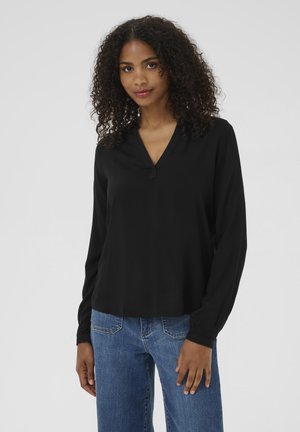 Black long-sleeve blouse with a V-neckline and subtle button detail. Textured fabric, relaxed fit, worn with blue denim jeans.