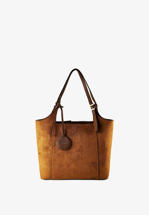 Bolso tote de ante marrón con correa de hombro ajustable y etiqueta circular de cuero colocada cerca de la parte superior.