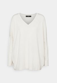 Pull en tricot surdimensionné couleur crème, avec décolleté en V, épaules tombantes et ourlet arrondi. Texture douce et coupe décontractée.