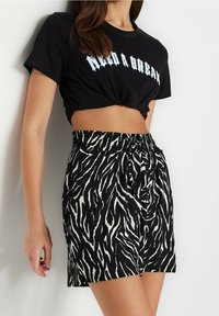 Sort cropped t-shirt med "Need a Break" trykt i blå, parret med sort-hvide zebra-stribede shorts med elastisk talje.