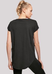 Black short-sleeve t-shirt with a curved hem, featuring a lightweight, soft texture and a relaxed fit. Back view highlights shoulder detail.