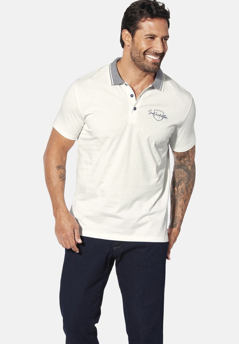 Weißes Polohemd mit Kragen, grauen Akzenten und marineblauen Knöpfen. Mit gesticktem Text und kurzen Ärmeln, kombiniert mit dunklen Jeans.