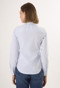 Camicia a righe blu chiaro e bianco con maniche lunghe, orlo arrotondato e colletto con bottoni, realizzata in tessuto liscio.