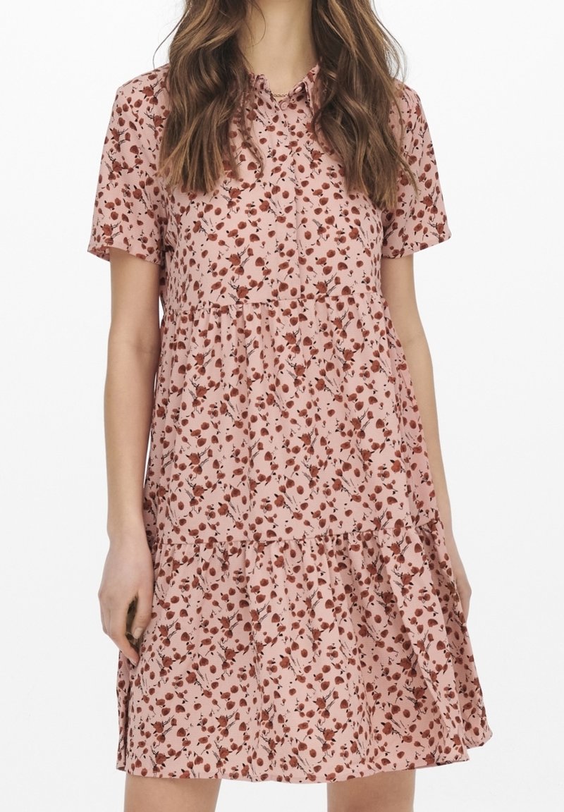 Rosa kortärmad klänning med ett blommönster i rött och brunt, med ett flerlagers volangdesign och knäppning vid halsen.
