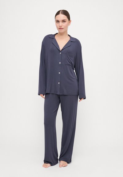 Navy pajama set featuring a button-up top with a pocket and long sleeves, paired with matching loose-fit pants, made of soft fabric with subtle stripes.