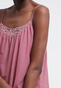 Rosa ärmelloses Oberteil aus leichtem Stoff mit einem gerafften Design und glitzernden Perlenakzenten entlang des Ausschnitts.