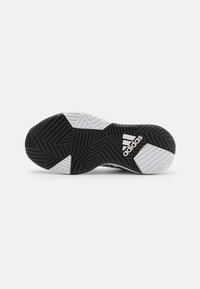 Semelle de chaussure de sport en noir et blanc avec un motif de semelle géométrique, présentant un caoutchouc noir texturé et des accents blancs, marquée "adidas." 