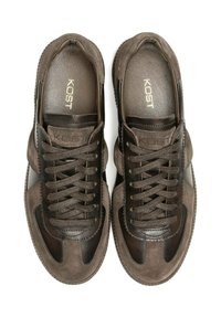 Baskets marron en cuir et daim, avec une forme ronde, une surface texturée, des lacets ronds et un logo sur la semelle intérieure.