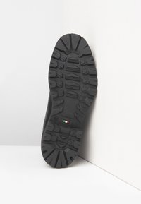 Sorte gummistøvlesål med dybe tracemønstre, NeroGiardini-branding, størrelse 42 og italiensk flag, der indikerer "Made in Italy".