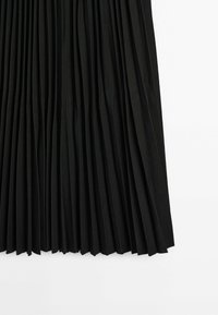 Jupe en tissu plissé noir avec des plis verticaux régulièrement espacés sur fond blanc.