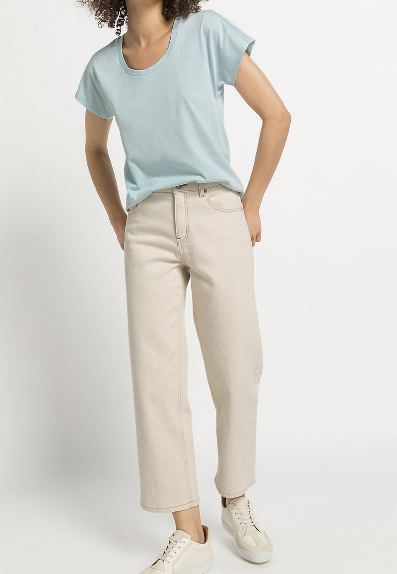Light blue short-sleeve t-shirt with a round neckline paired with beige wide-leg jeans. The outfit is complemented by white sneakers.