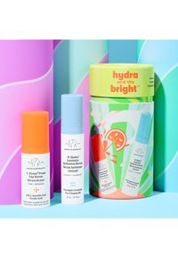 Three skincare serums in colorful cylindrical bottles with pops of orange, blue, and white, packaged in a vibrant, decorative box.