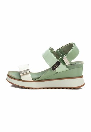Sandalia cuña con correas brillantes en verde y blanco, un hebilla metálica cuadrada y una suela texturizada. Presenta un tacón ligeramente elevado.