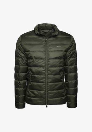 Giacca trapuntata verde scuro con zip, colletto alto e logo GANT sul petto, dotata di tasche laterali con zip e cuciture orizzontali.