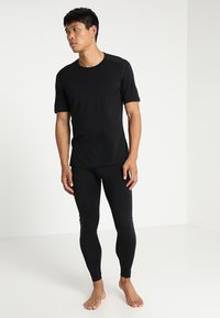Juodas sportinis marškinėlis trumpomis rankovėmis ir apvaliu kaklu, derinamas su juodomis leggins. Lygus paviršius, prigludęs fasonas, be matomų raštų.