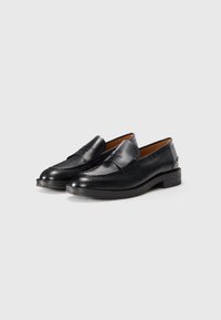 Mocassins en cuir noir avec un bout arrondi, dotés d'un détail cousu sur le dessus et d'un talon solide et bas pour la stabilité.