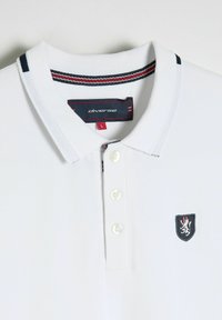 Biała koszulka polo z trzyguzkowym zapięciem, kontrastującym kołnierzykiem w niebiesko-czerwone paski oraz wyszywanym emblematem na piersi.