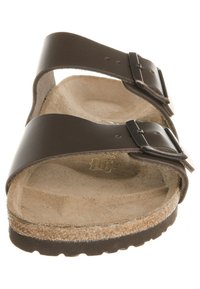 Sandalo in pelle marrone con due cinturini regolabili e fibbie in argento. Fodera in sughero con superficie testurizzata, suola piatta in gomma.
