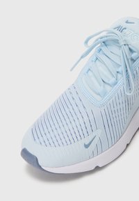 Svijetloplavi Nike Air 270 tenisice s prednje strane, izrađene od pletene tkanine, vezice vezane u mašnu, mali swoosh logo na prstu i jeziku, bijela potplata vidljiva.