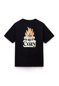 Lyhythihainen musta t-paita, jossa on grafiikkaa hukassa ja oransseja liekkejä sanan "Cozy" yläpuolella takana.