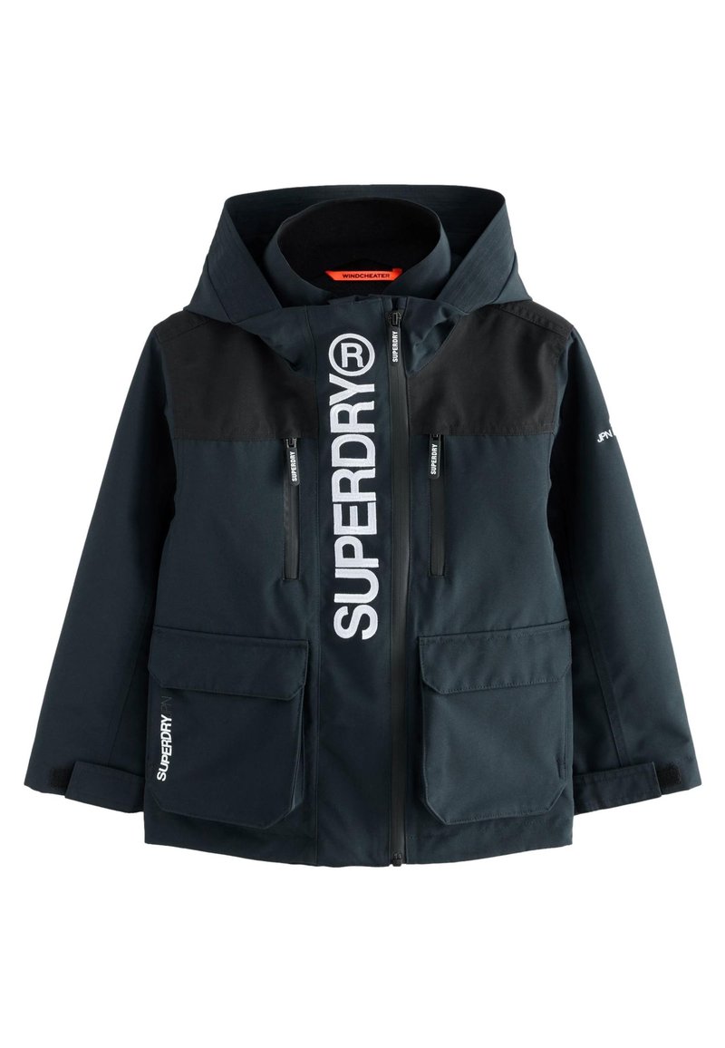 Must ja tumesinine tuulekindel jope lukuga ees, valge ülisuur logo ja neli taskut. Varustatud kapuutsi ja tekstuursete paneelidega.