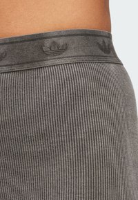 Gray ribbed fabric athletic waistband with a subtle embossed logo pattern. Smooth texture and fitted design for comfort and support.