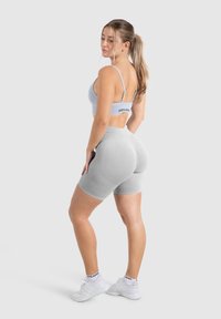 Lichtgrijze sportset met een bralette met verstelbare banden en high-waisted biker shorts, beide naadloos en snug-fitting.