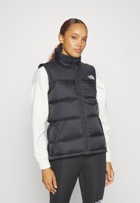 Μαύρο γιλέκο πούφ με ψηλό γιακά και φερμουάρ, διακοσμημένο με οριζόντιο καπιτονάρισμα και λογότυπο στην αριστερή πλευρά του στήθους.