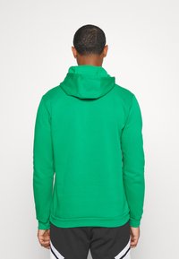 Hoodie vert en tissu mélangé de coton. Il dispose d'une capuche avec cordon de serrage, de manches longues et d'une taille ajustée avec des poignets côtelés.