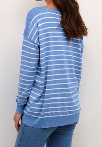 Pull rayé bleu avec des lignes blanches horizontales, coupe ample, manches longues, poignets et ourlet côtelés, fabriqué en maille douce.