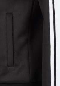 Černá sportovní bunda s skrytou kapsou, kontrastními bílými bočními pruhy a strukturovaným povrchem.