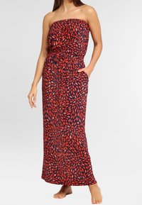 Maxi šaty v námořnické modři s červeným listovým vzorem, korzet bez ramínek, elastický pas a boční kapsy. Proudná látka s hladkou texturou.