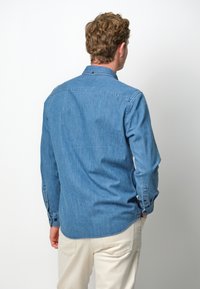 Lichtblauwe denim overhemd met een button-down kraag, lange mouwen en knopenmanchetten. Heeft een gebogen zoom en subtiele textuur.