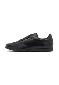 Sneakeruri de piele negre cu talpa joasă, șireturi negre, detalii minime de cusut și talpă din cauciuc plat, orientate spre stânga pe un fundal alb.