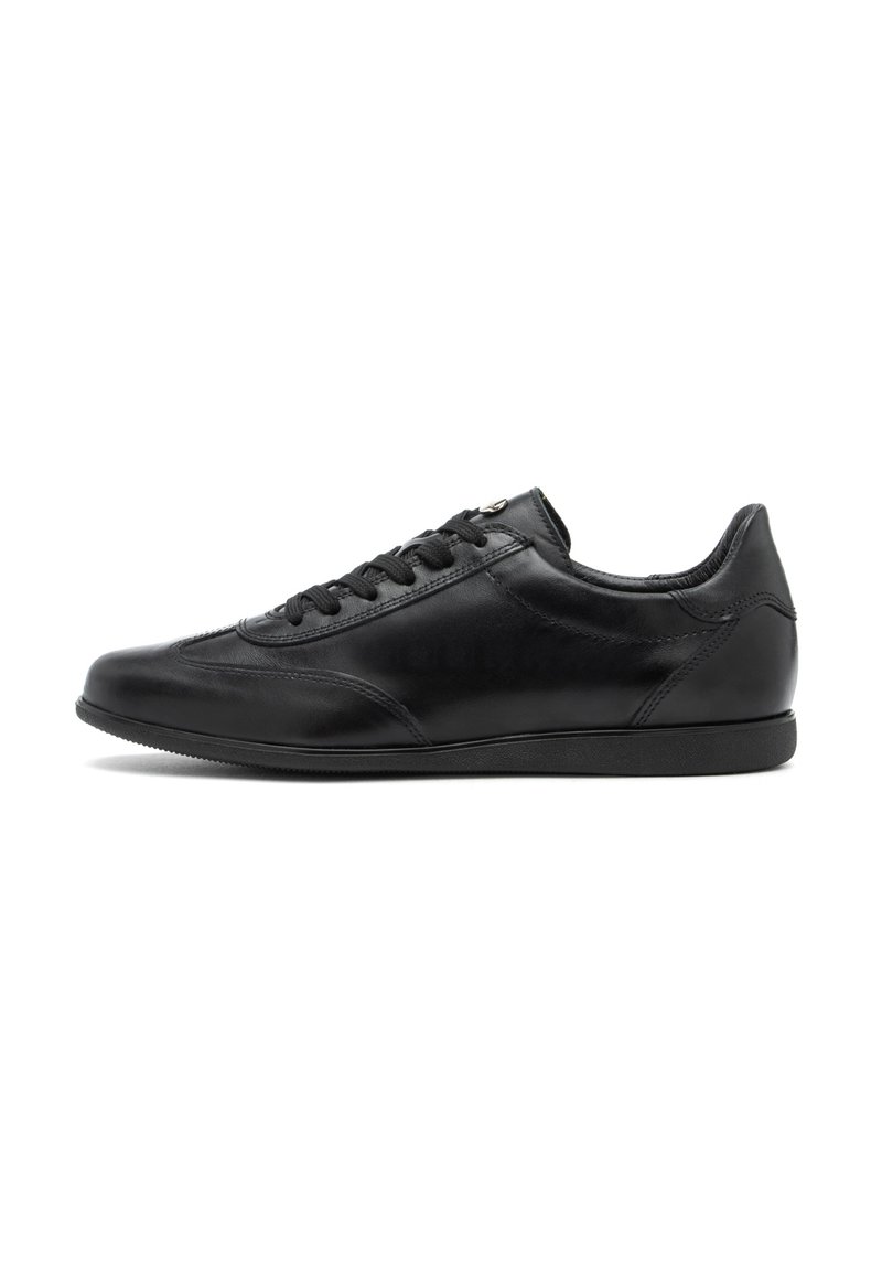 Sneakeruri de piele negre cu talpa joasă, șireturi negre, detalii minime de cusut și talpă din cauciuc plat, orientate spre stânga pe un fundal alb.