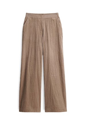 Hand hebt dunkelbraunen, geknöpften Pullover an und enthüllt die Taille über hochgeschnittenen, strukturierten beigen Hosen.
