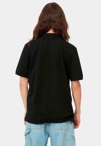 Schwarzes Baumwoll-T-Shirt mit kurzen Ärmeln, ausgestattet mit einem klassischen Kragen und einem lässigen Schnitt, von hinten betrachtet. Einfaches und unauffälliges Design.