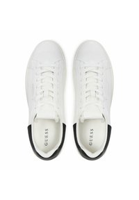 Sneaker bianchi in pelle con punta arrotondata, lacci piatti e dettagli neri sul tallone. L'interno presenta il marchio "GUESS" stampato in nero.