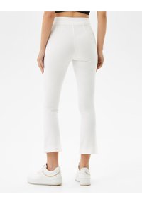 Vita utsvängda byxor med hög midja, tillverkade av ett slätt tyg. Har sömdetaljer och en ren avslutning vid fållen. Matcher med vita sneakers.