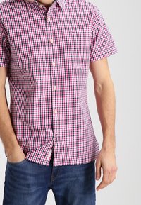 Camicia a maniche corte con bottoni, in tessuto a quadretti rosa e navy, con colletto standard e orlo curvo. Tessuto di cotone casual.