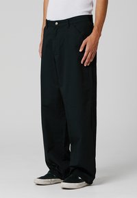 Zwarte wijde broek van katoen, met een geknoopte tailleband, zijzakken en een zachte, matte textuur.