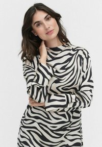 Robe à motifs zébrés noir et crème. Manches longues avec larges poignets, col montant et tissu doux. Texture lisse, design fluide.